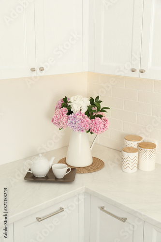 Beautiful bouquet of hydrangea flowers and tea on light countertop