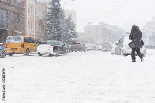 Adult man passing the winter city road in heavy snowy storm.