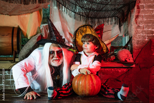 Father and son playing scary Halloween games at home. Father and son in carnival costumes are waiting for guests and sweets. Family party on Halloween. Halloween at home.