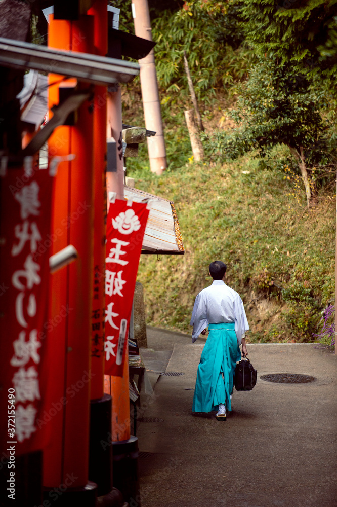 Men dress like Shinto priests, wearing white shirts and green pants. Rear view, walking on a walkway in Fushimi Inari Shrine. Men dress like Shinto priests, wearing white shirts and green pants. Rear view, walking on a walkway in Fushimi Inari Shrine.