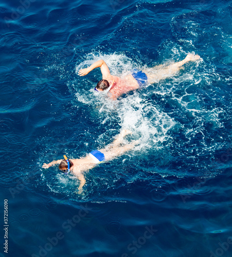People swim in the blue water of the sea