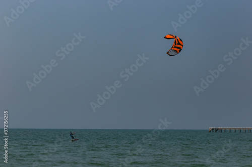 A surfboard is surfing on the sea near the long bridge in Pattaya beach of eastern in Thailand on a long holiday.