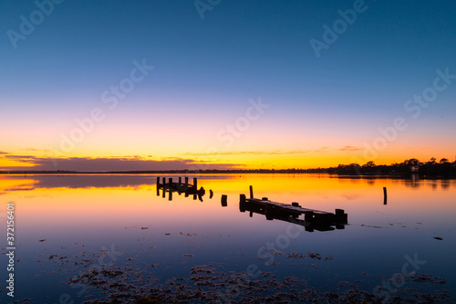 A broken wooden pier on the lake at dawn, Gorokan, Australia.