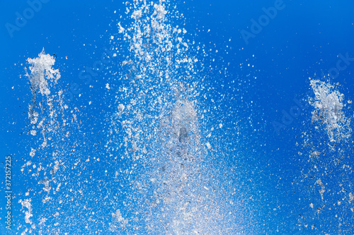 Splashing water from a fountain on a background of blue sky