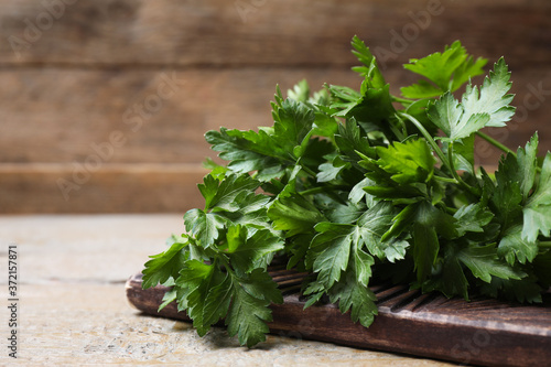Board with fresh green parsley on wooden table, closeup