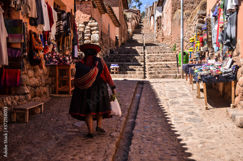 Woman in traditional Peruvian clothings walking in Chinchero, Peru. © Andr