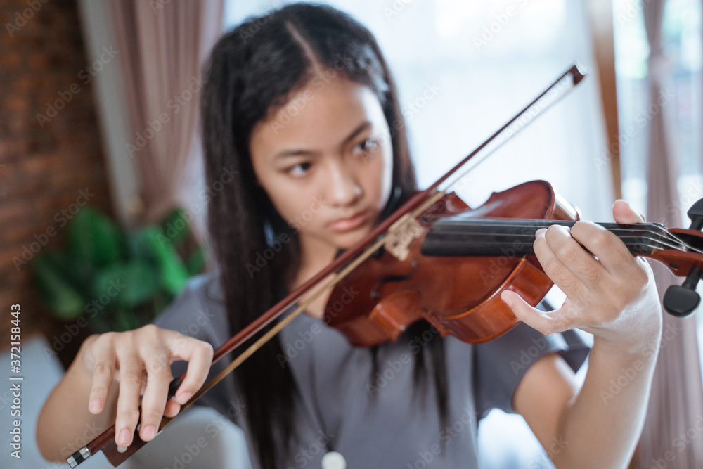 close up of beautiful girl playing violin with violin bow indoors at home close up of beautiful girl playing violin with violin bow indoors at home