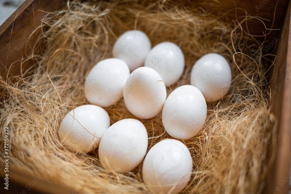 Eco-product. A wooden box of hay containing ten white eggs, neatly arranged. The view from the top. The concept of natural and farm food