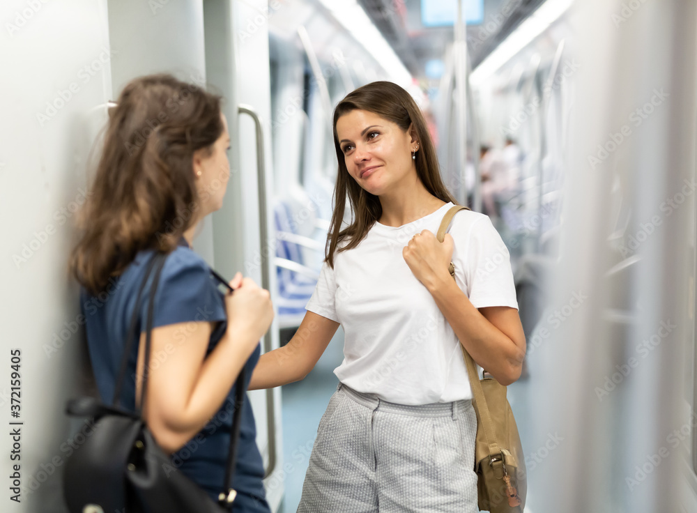 Obraz premium Two girlfriends enjoying friendly conversation while traveling on subway train..