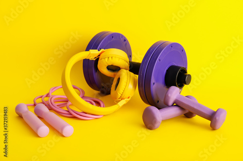 Fototapeta Naklejka Na Ścianę i Meble -  Different sports equipment with headphones on color background