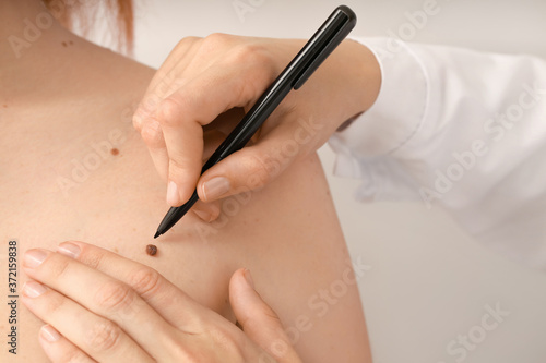 Dermatologist examining patient on grey background