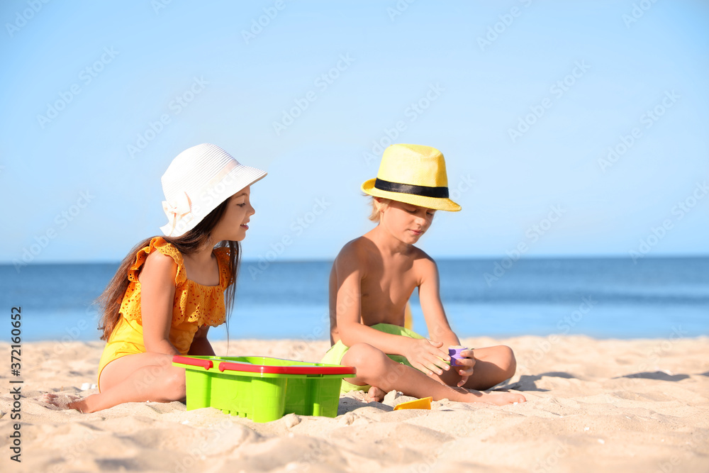 Cute little children playing with plastic toys on sandy beach
