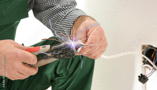 Fotografia Electrician receiving electric shock while working, closeup