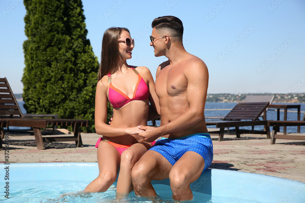 Happy couple sitting at poolside on sunny summer day Happy couple sitting at poolside on sunny summer day