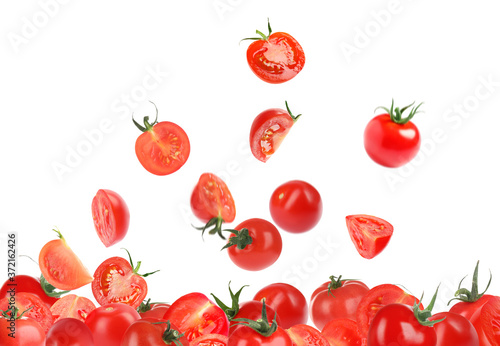 Many cut and whole tomatoes falling on white background