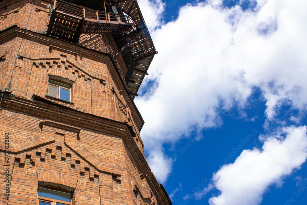old water tower made of ancient bricks on a background of blue sky with clouds