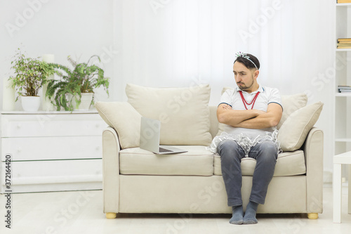 Young single father overwhelmed with household chores sitting on sofa in living room.
