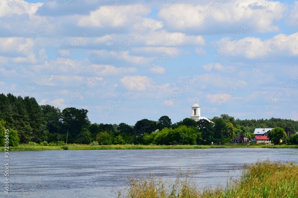 A beautiful view of the peaceful Narew river. Sunny, summer day at the river Narew in polish countryside. River in western Belarus and north-eastern Poland, is a right tributary of the Vistula River. A beautiful view of the peaceful Narew river. Sunny, summer day at the river Narew in polish countryside. River in western Belarus and north-eastern Poland, is a right tributary of the Vistula River.