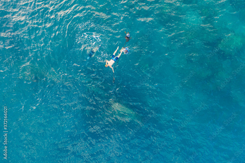 Three people snorkling in the ocean in Amed, Bali, Indonesia