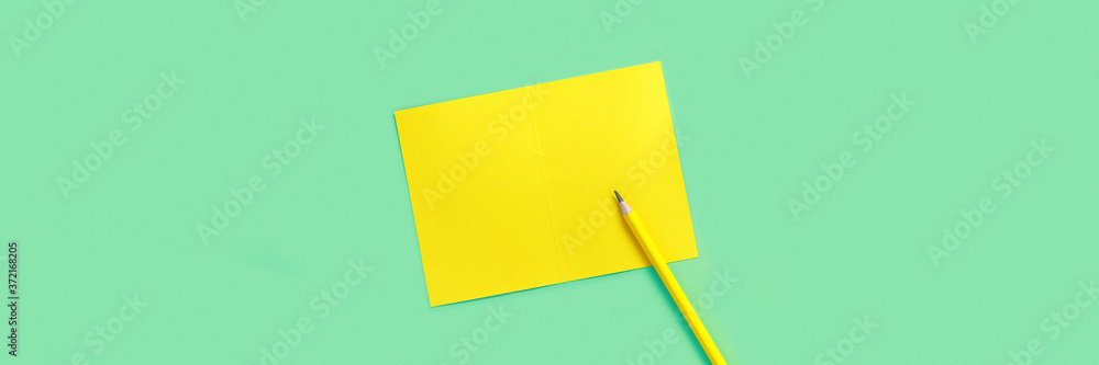 Pencil and sheet of yellow paper for text on green background. Pencil and sheet of yellow paper for text on green background.