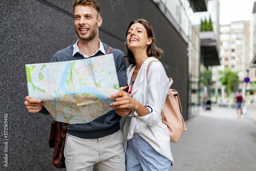 Happy smiling woman and man in love walking with map in the city