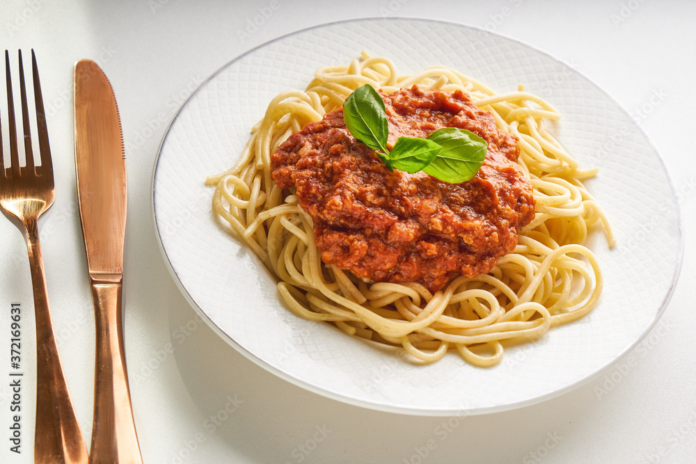 Traditional pasta bolognese served on a white plate and garnished with basil Traditional pasta bolognese served on a white plate and garnished with basil