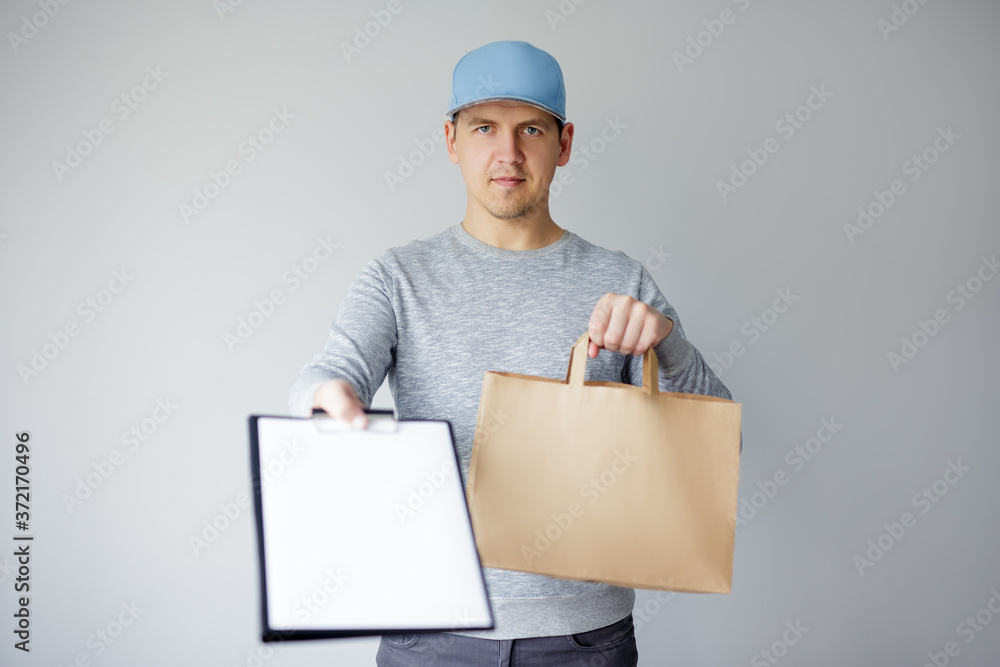 delivery man holding paper bag and showing clipboard to confirm receiving of order from food delivery company delivery man holding paper bag and showing clipboard to confirm receiving of order from food delivery company