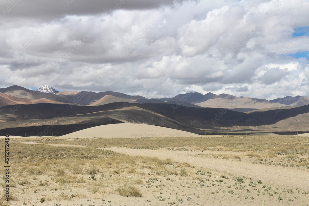 View of the mountain and sand dune with dirt road near Tingri on the way to Everest Base Camp, Tibet, China