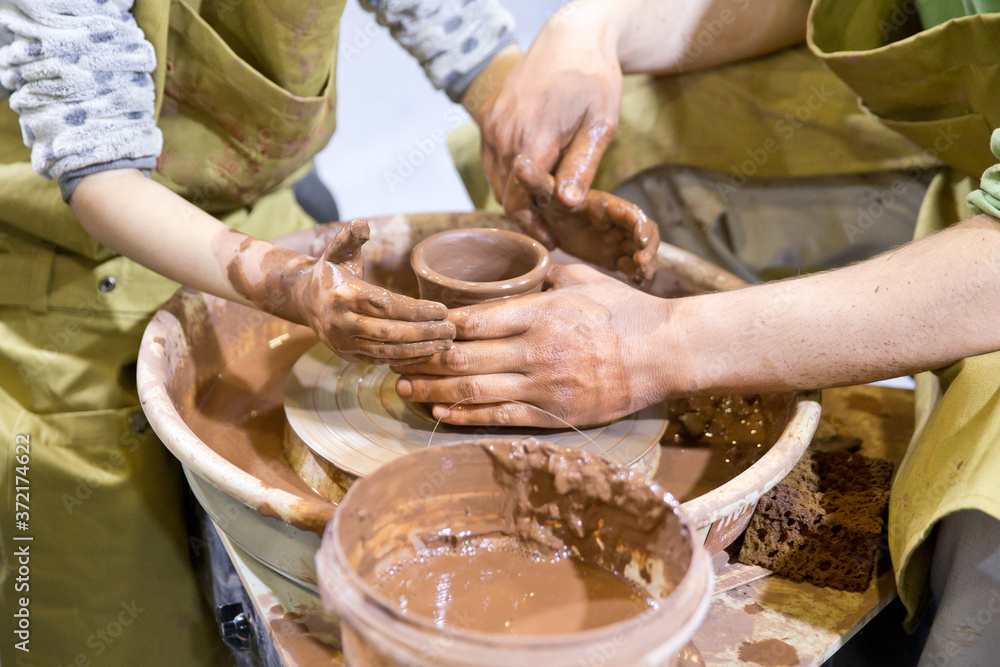 Hands on a pottery wheel. Potter hand. Clay potter creating on the pottery wheel Hands on a pottery wheel. Potter hand. Clay potter creating on the pottery wheel