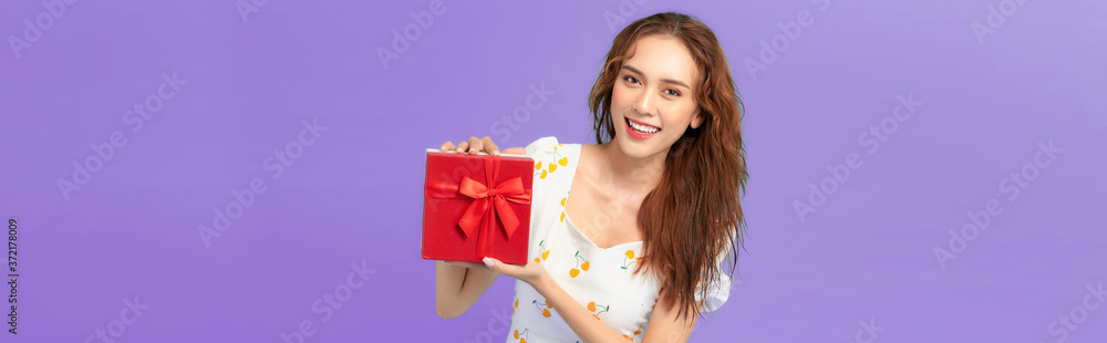 Happy smiling girl in dress holding present box and over blue background Happy smiling girl in dress holding present box and over blue background