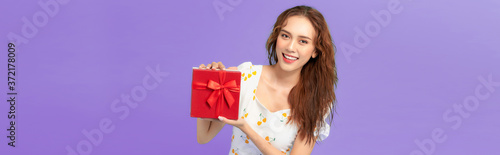 Happy smiling girl in dress holding present box and over blue background