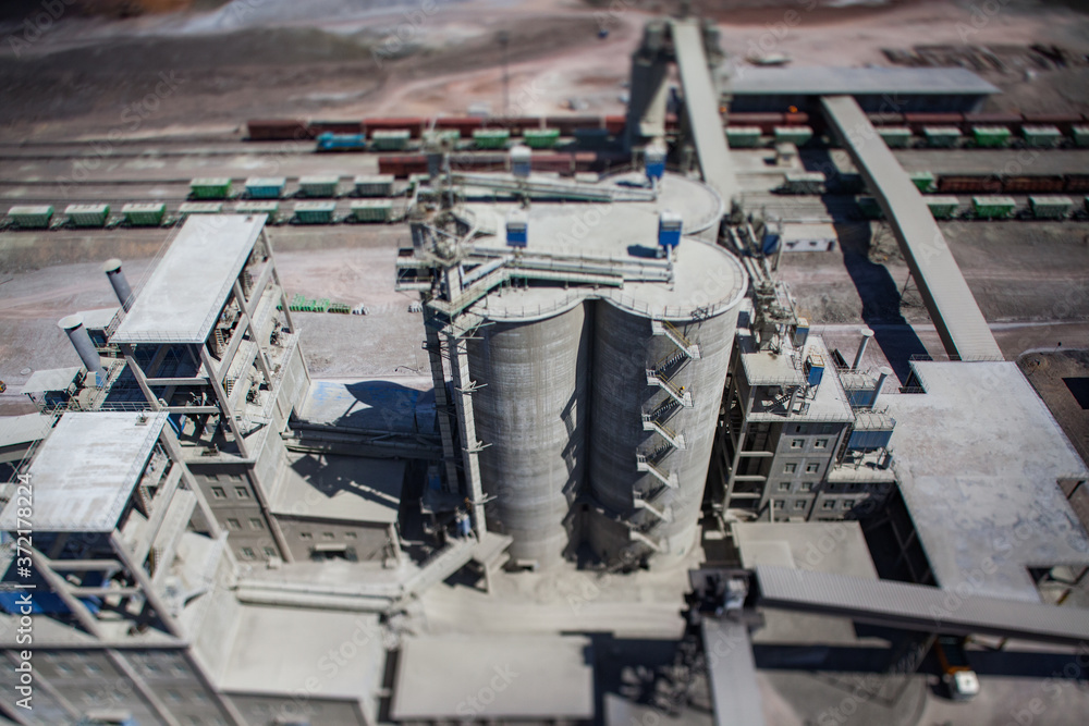 Mynaral/Kazakhstan: Modern cement plant in desert. Silos and factory buildings and conveyor and  cargo train terminal. tilt-shift partially blurred photo.