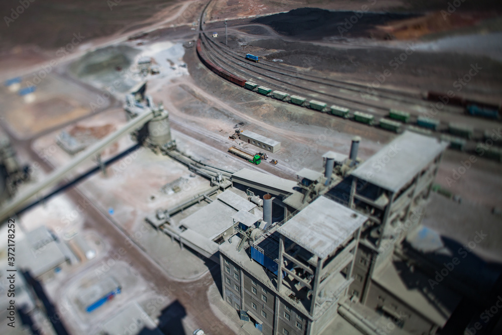 Mynaral/Kazakhstan: Jambyl Cement plant. Aerial view on long truck on railway terminal and factory buildings. Tilt-shifted view.