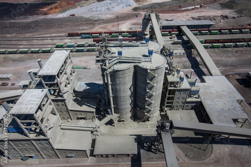 Mynaral/Kazakhstan: Jambyl Cement plant. Aerial view on railway terminal with hopper cars train and cement silos and pile of clinker minerals.