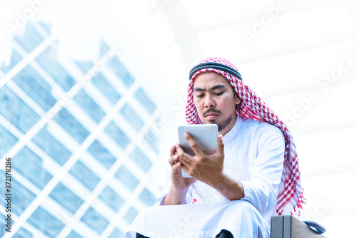 Islamic man using smartphones app organize schedule agenda  focus on hands holding smartphone muslim modern uae city. Arab men wear hijab and muslim formal dress sending text sms online lifestyle photo