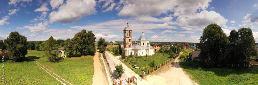 an old manor house turned into ruins of red brick and a church removed from a drone