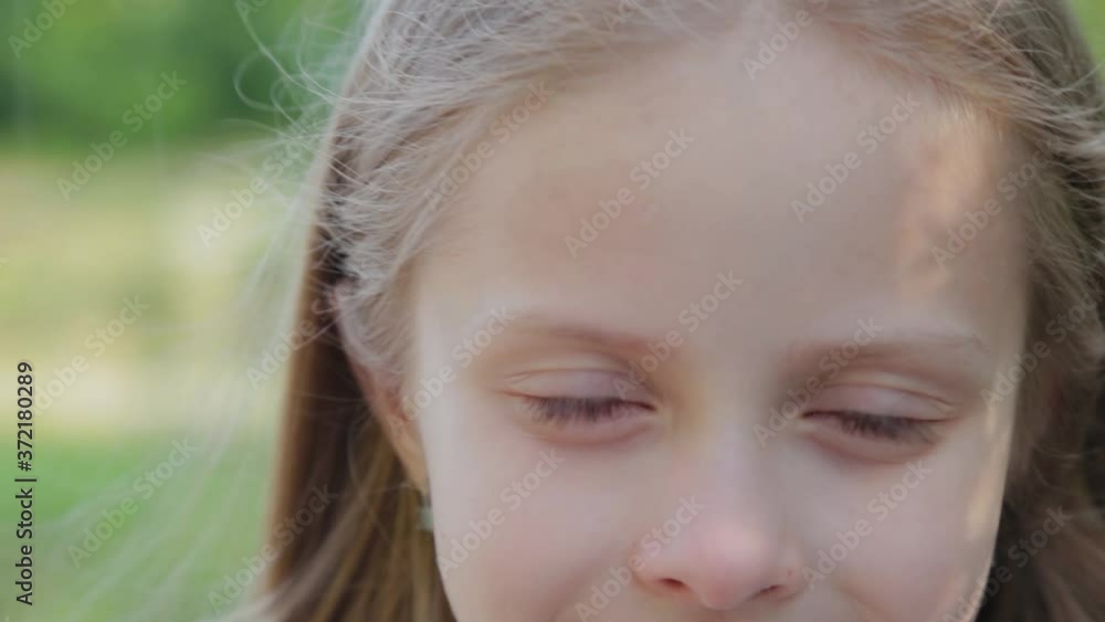 A beautiful girl stands by the green bushes. Portrait of a little girl. A beautiful girl stands by the green bushes. Portrait of a little girl.