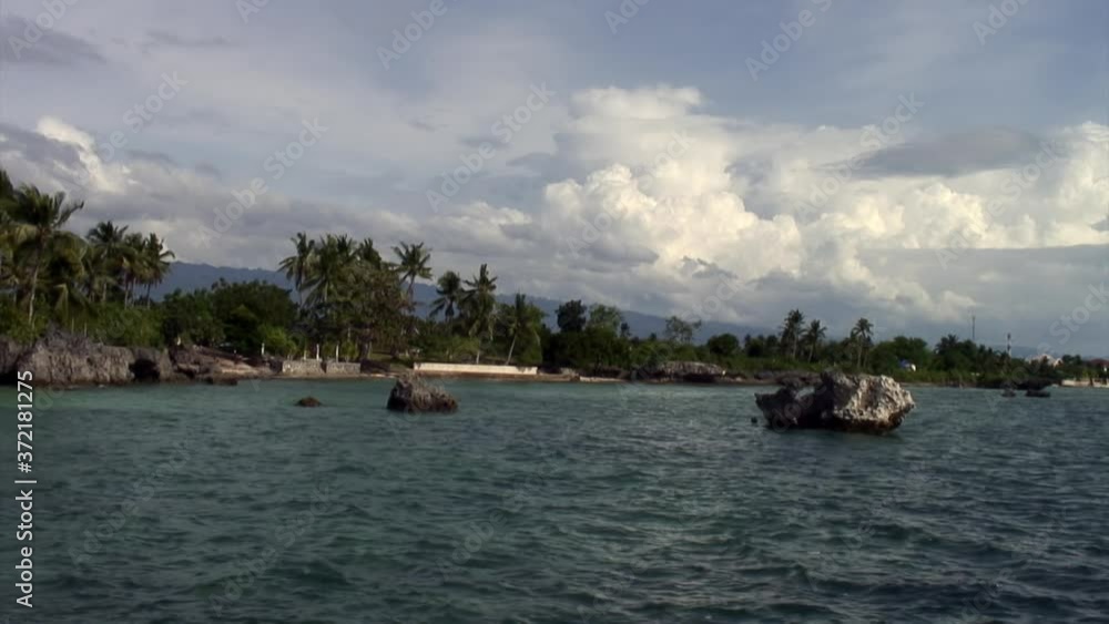 Shoreline landscape with palm trees on background of blue sky and white clouds on islands of Republic of Philippines. Shoreline landscape with palm trees on background of blue sky and white clouds on islands of Republic of Philippines.