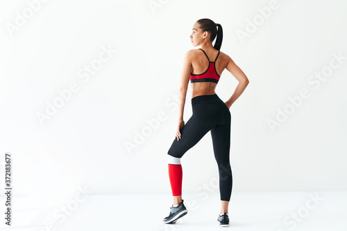 Back view of young woman in sportswear on white background with copy space