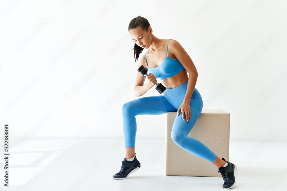 Fototapeta premium Sporty woman in sportswear doing exercise with dumbbells on white background with copy space
