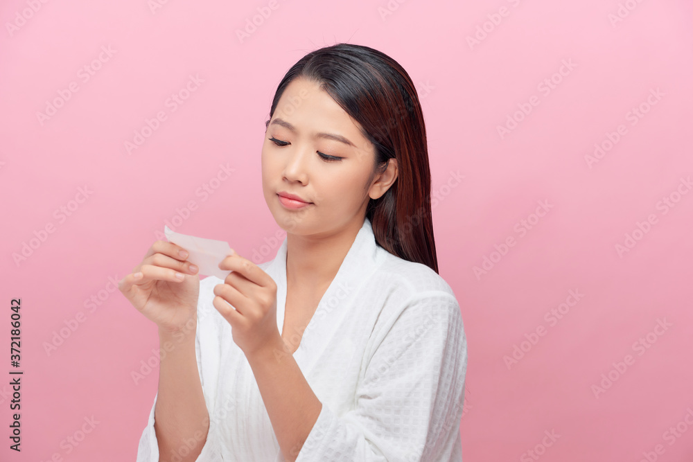 Closeup of beautiful asian girl model with natural face makeup looking at oil absorbing tissue Closeup of beautiful asian girl model with natural face makeup looking at oil absorbing tissue