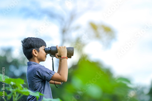 little Indian boy enjoys in nature with binoculars