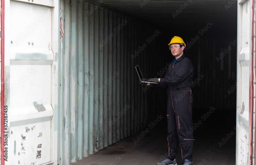 Young worker man with laptop at container terminal port warehouse for check stock product. Young worker man with laptop at container terminal port warehouse for check stock product.