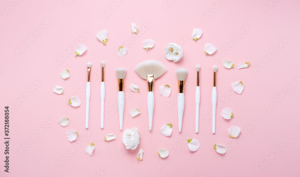 Makeup brushes and flowerss on white background. Horizontal view copyspace.