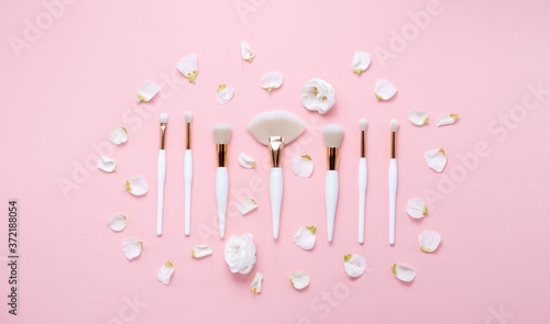 Makeup brushes and flowerss on white background. Horizontal view copyspace. © Elina