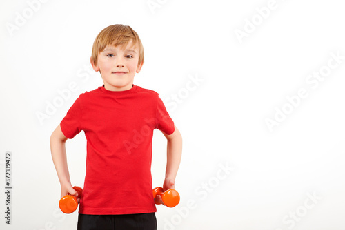 Schoolboy training with dumbbells, isolated on white. Physical training for kids. Healthy childhood. Fitnesss for children. Copy space. photo