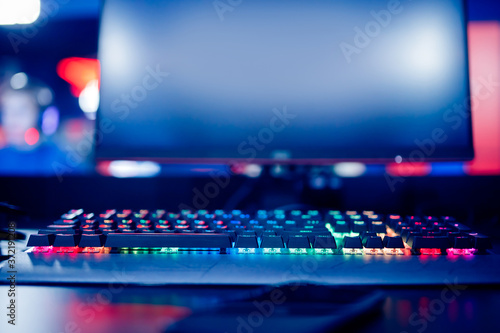 Professional cyber video gamer studio room with personal computer armchair  keyboard for stream in neon color blur background. Soft focus