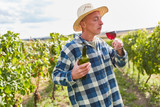 Weinbauer mit einem Glas Rotwein im Weinberg