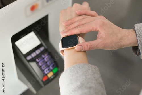 Woman paying at cafe with smart watch wirelessly on easy POS terminal