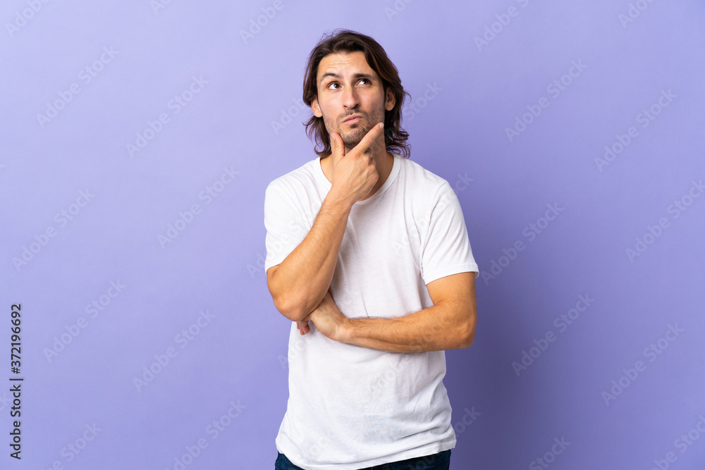 Young handsome man isolated on purple background thinking an idea while looking up Young handsome man isolated on purple background thinking an idea while looking up